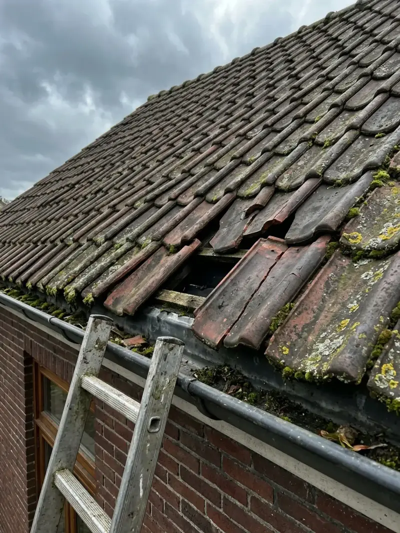 Schuin dak met verschoven en gebroken dakpannen na een storm
